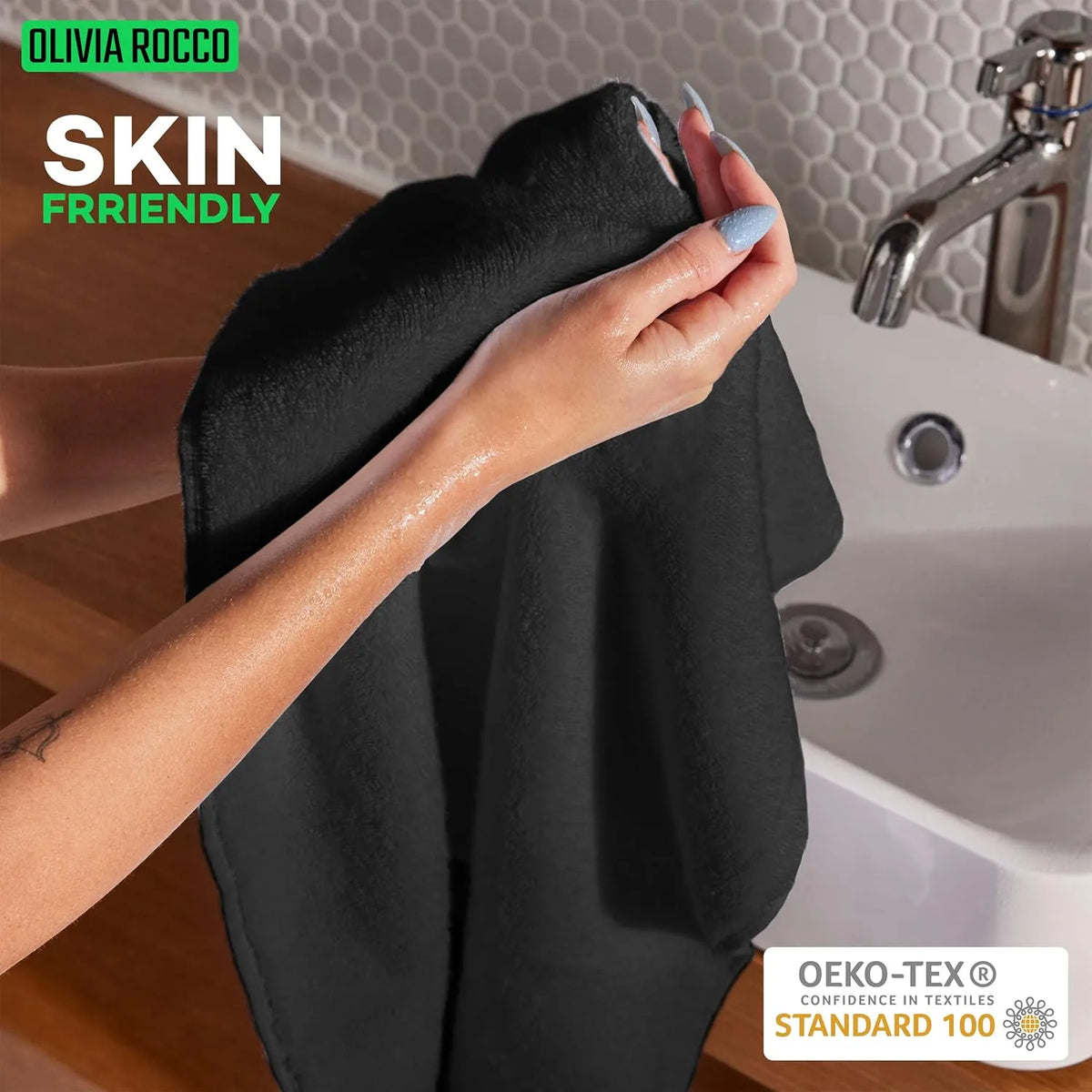 Person holding a black towel with a sink and faucet in the background, featuring 'Olivia Rocco' branding and OEKO-TEX certification.