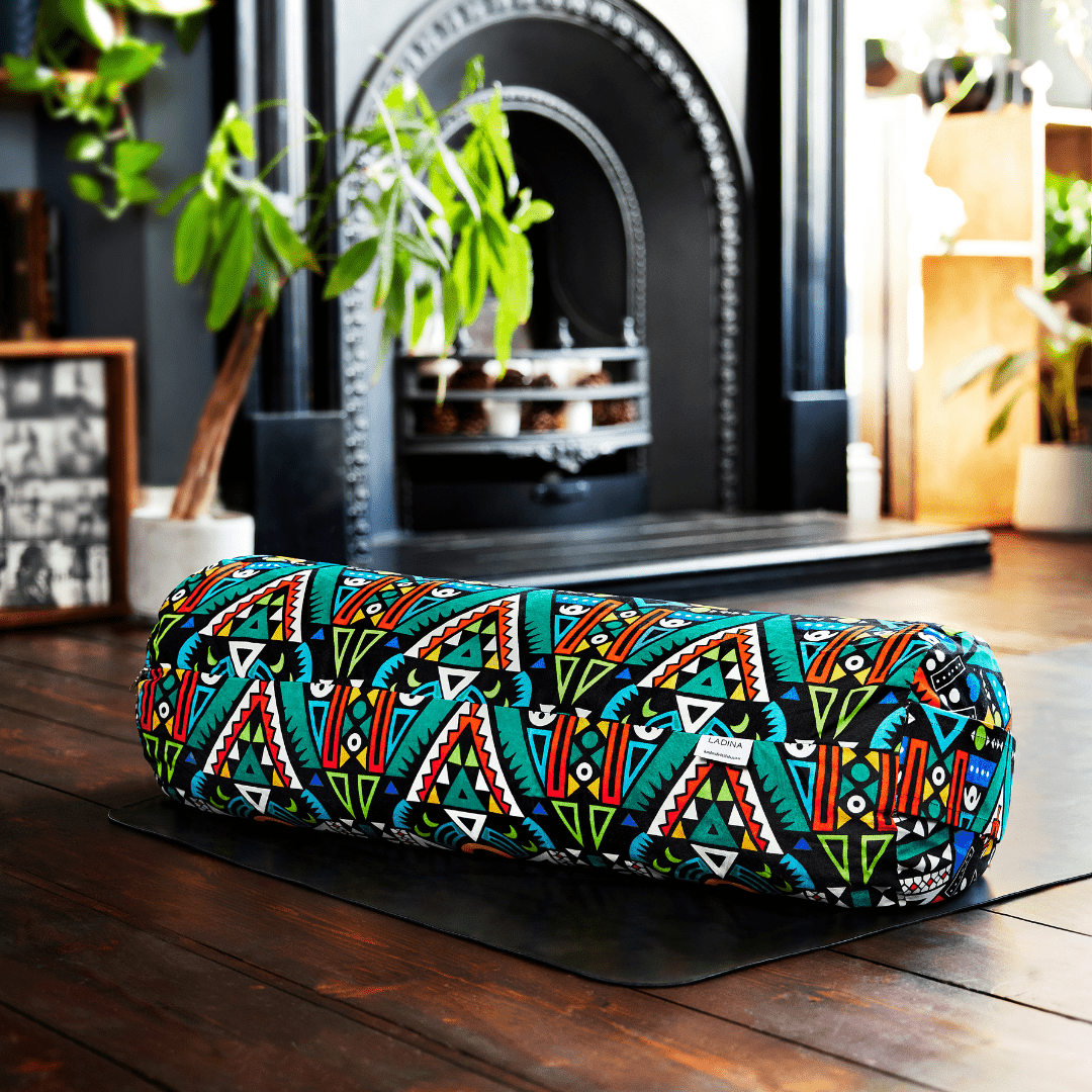 Colourful yoga bolster with geometric pattern on a wooden floor.
