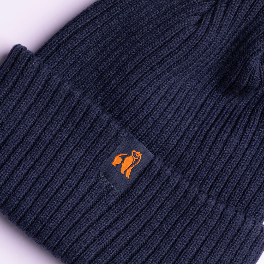 Navy blue knit beanie with a logo patch on a white background