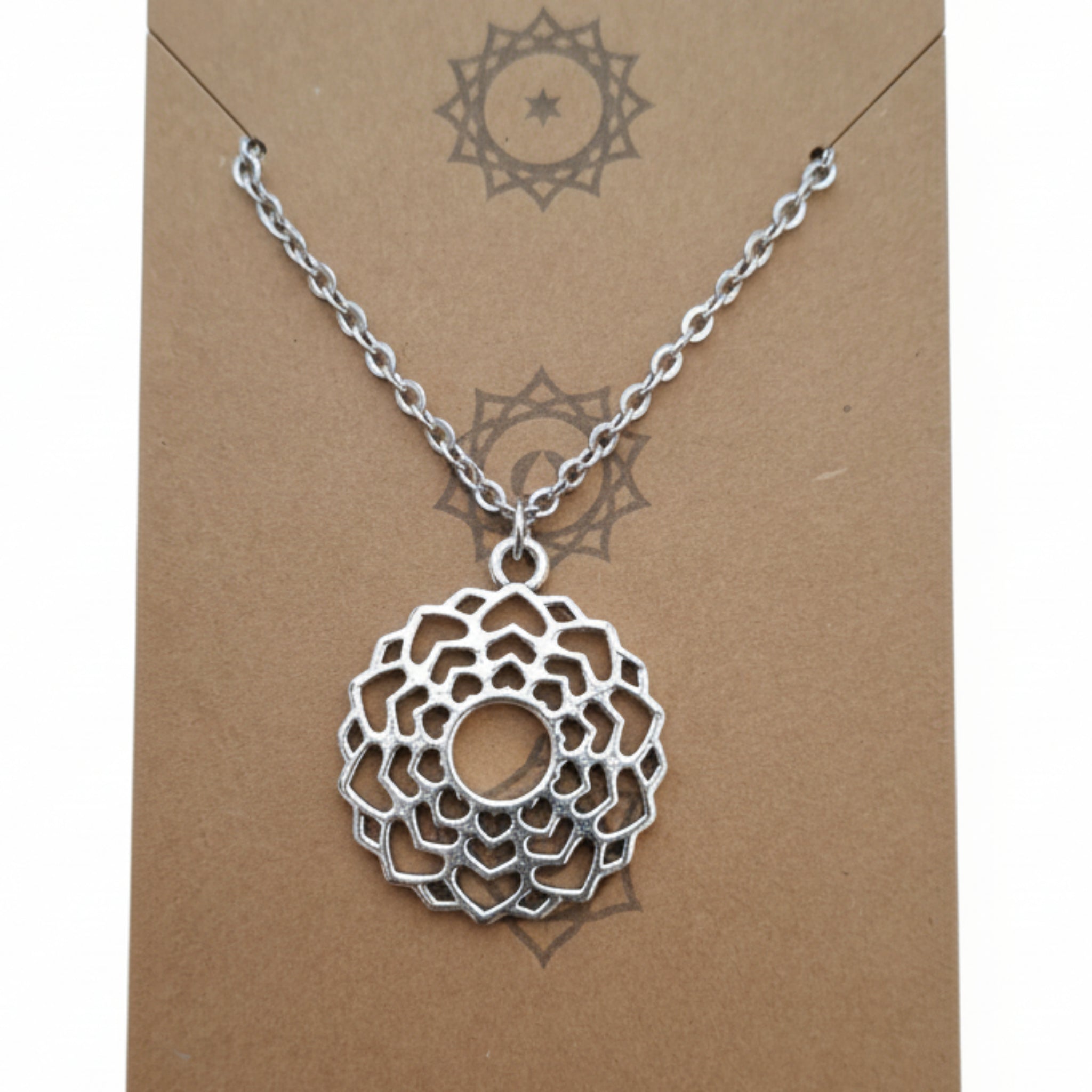 Silver necklace with a intricate pendant on a brown card