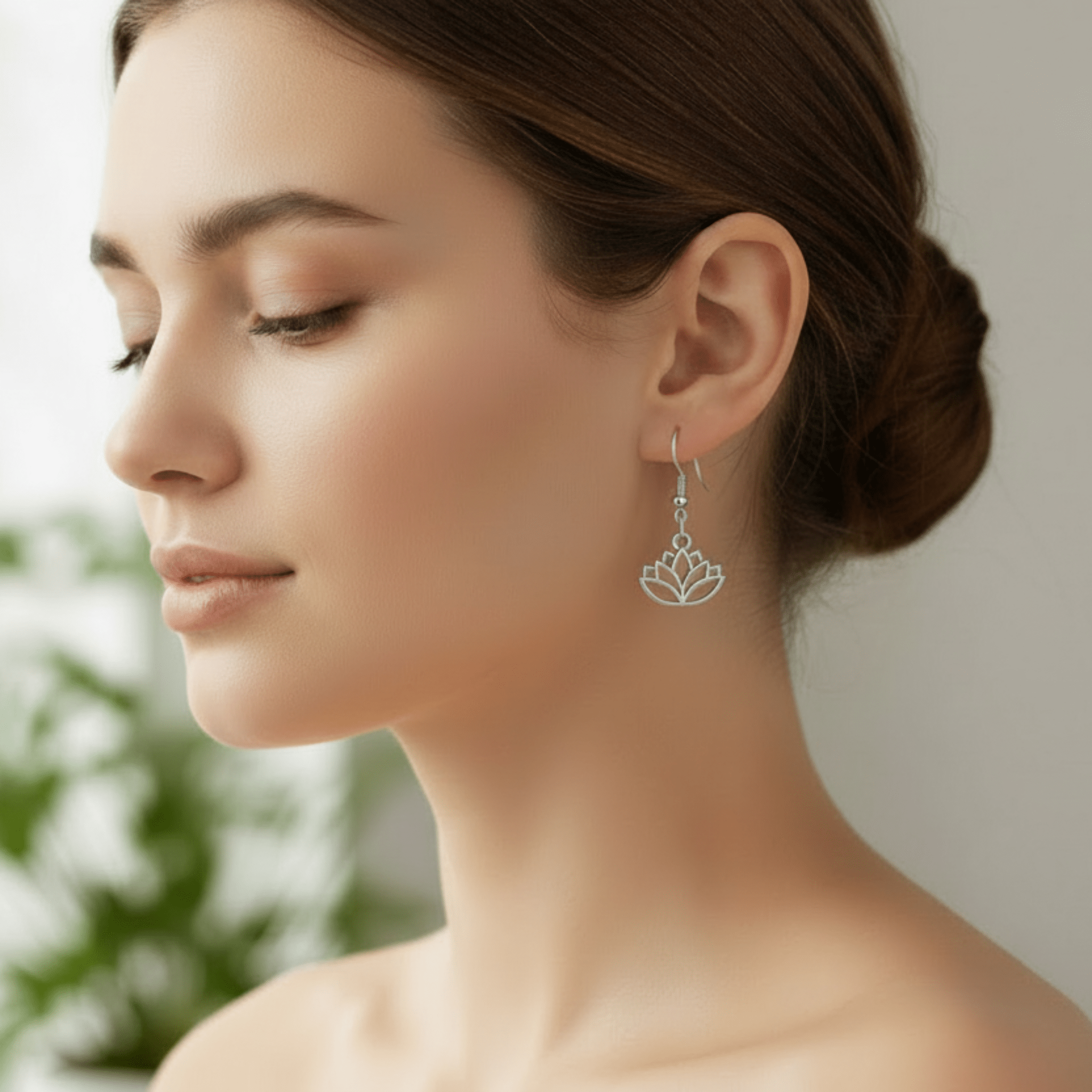 Woman wearing a silver lotus flower earring with a blurred green plant background