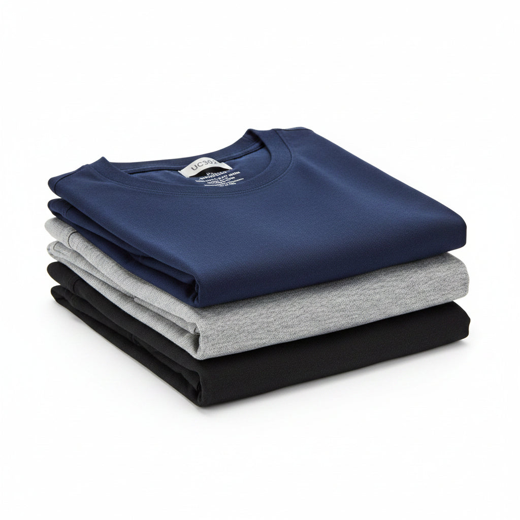 Stack of folded cotton t-shirts for men in navy, grey, and black on a white background