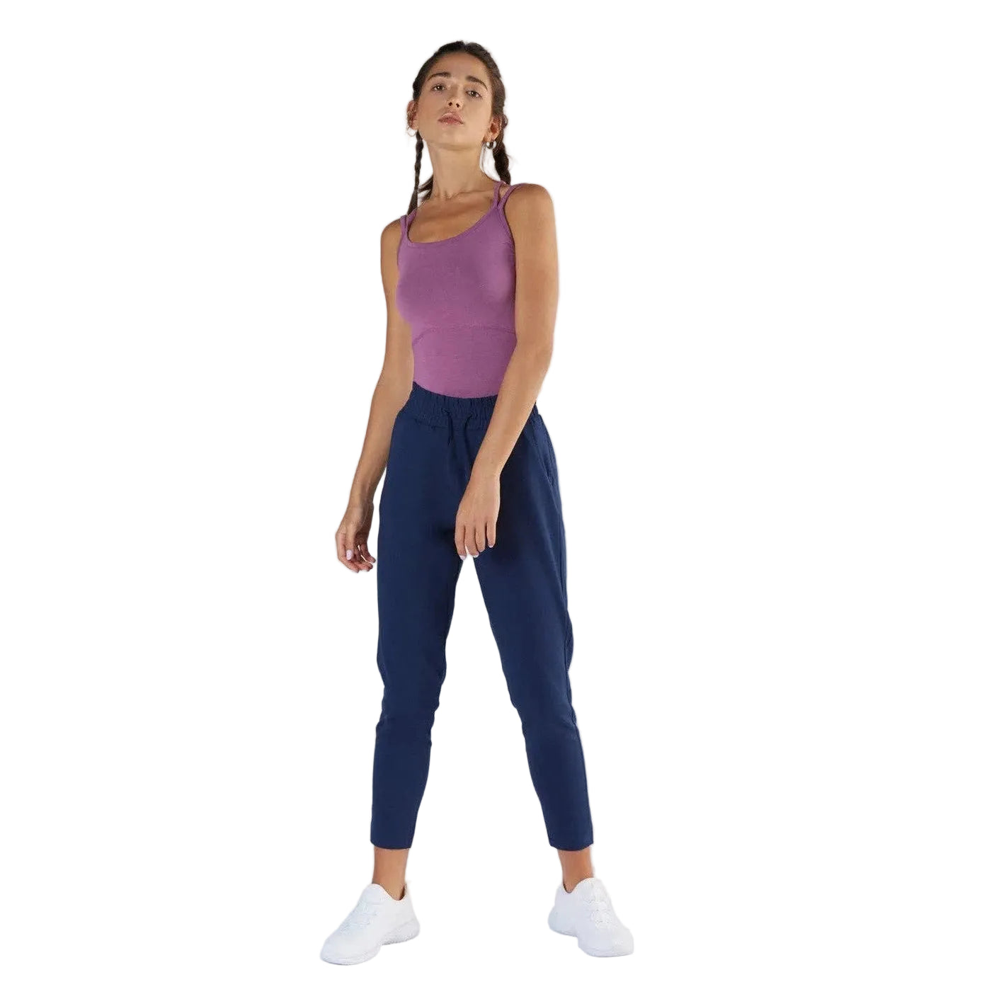 Woman wearing a purple tank top and navy jogger pants on a white background