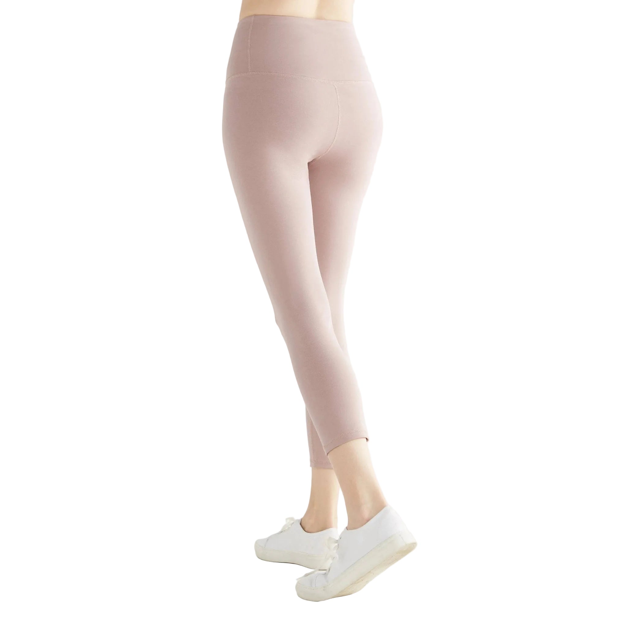 Person wearing light pink leggings and white sneakers on a white background