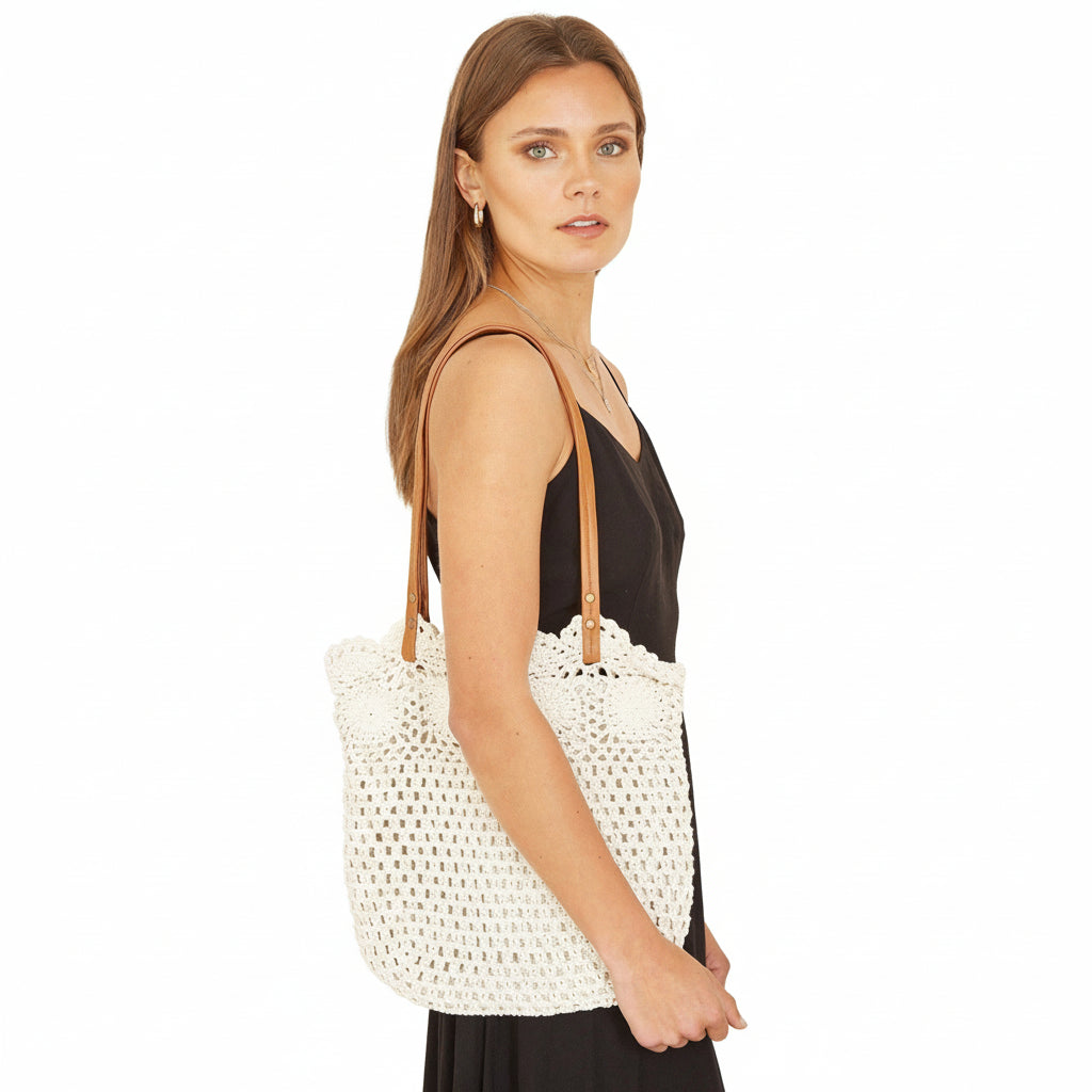 Woman holding a white woven bag against a plain background