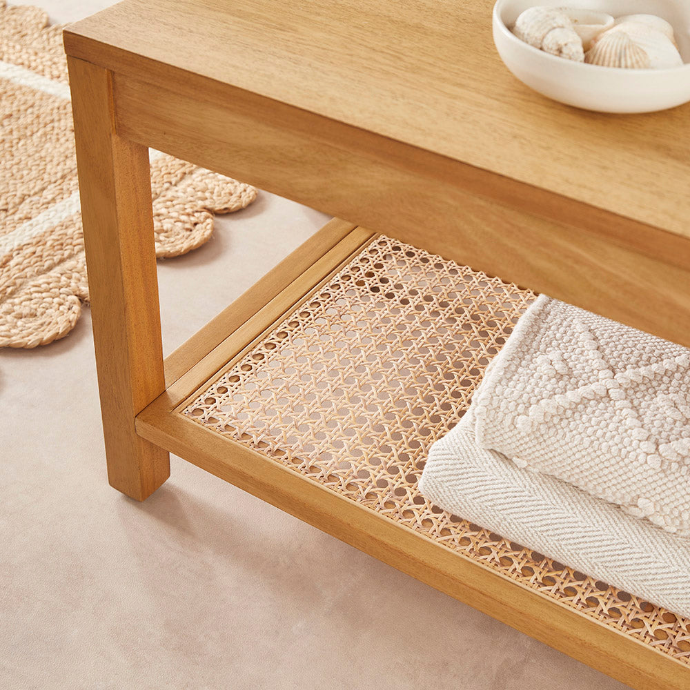 Wooden shelf with woven bottom shelf and white towel on a neutral background