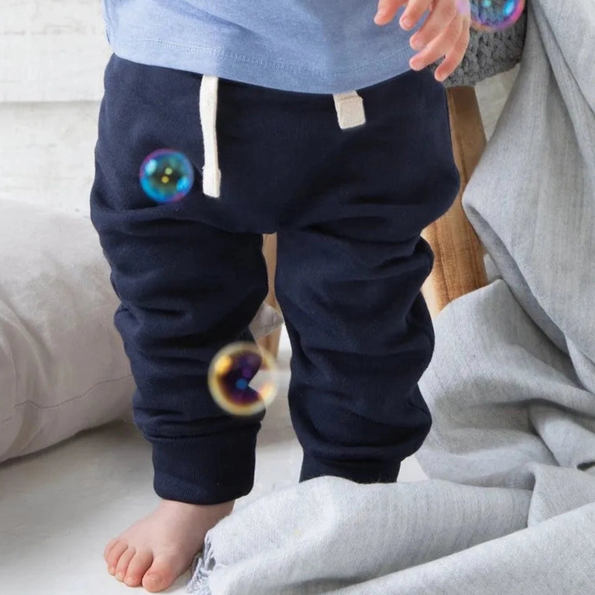 Child wearing navy blue pants with bubble designs on a light background