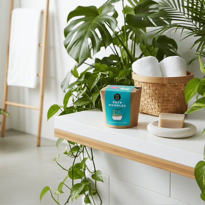 A box of bath noodles on a white surface with plants in a bright room