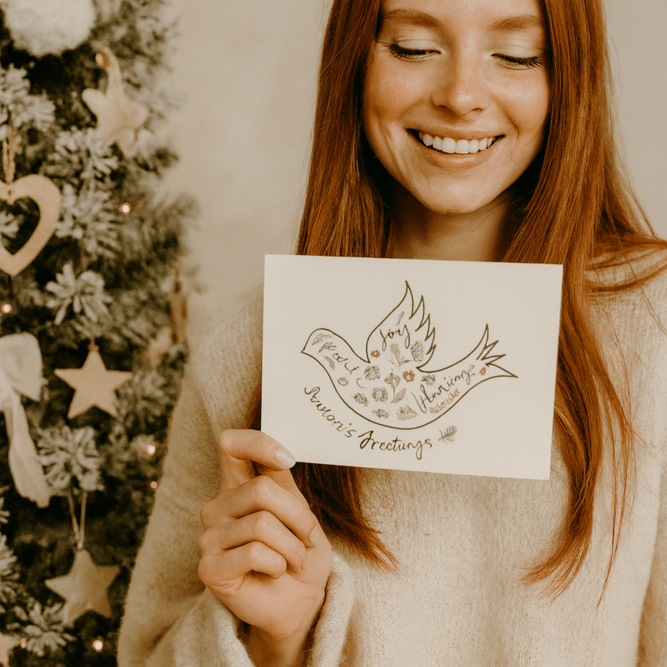 Woman holding a card with a Christmas tree in the background