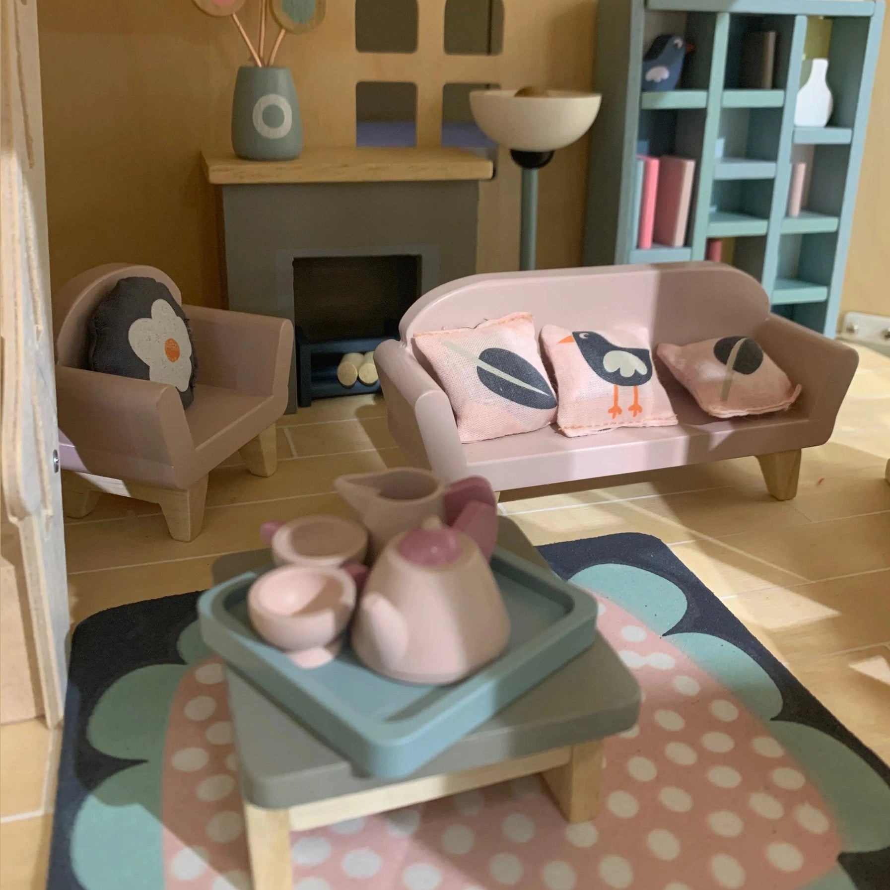Children's dollhouse living room with toy furniture, rug, and decor.