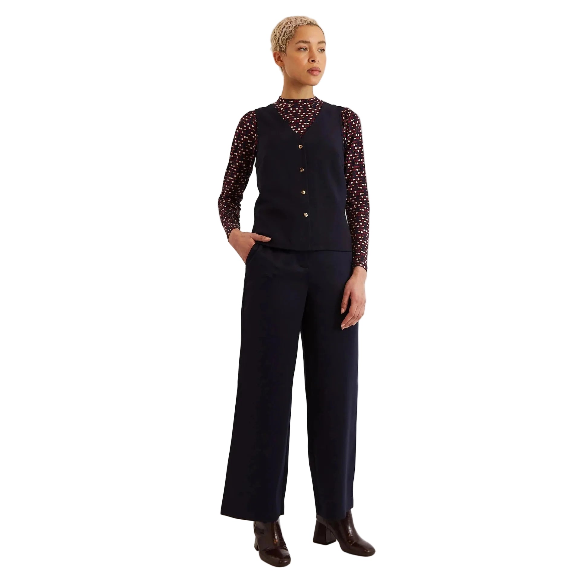 Person wearing a dark outfit with a patterned top on a white background