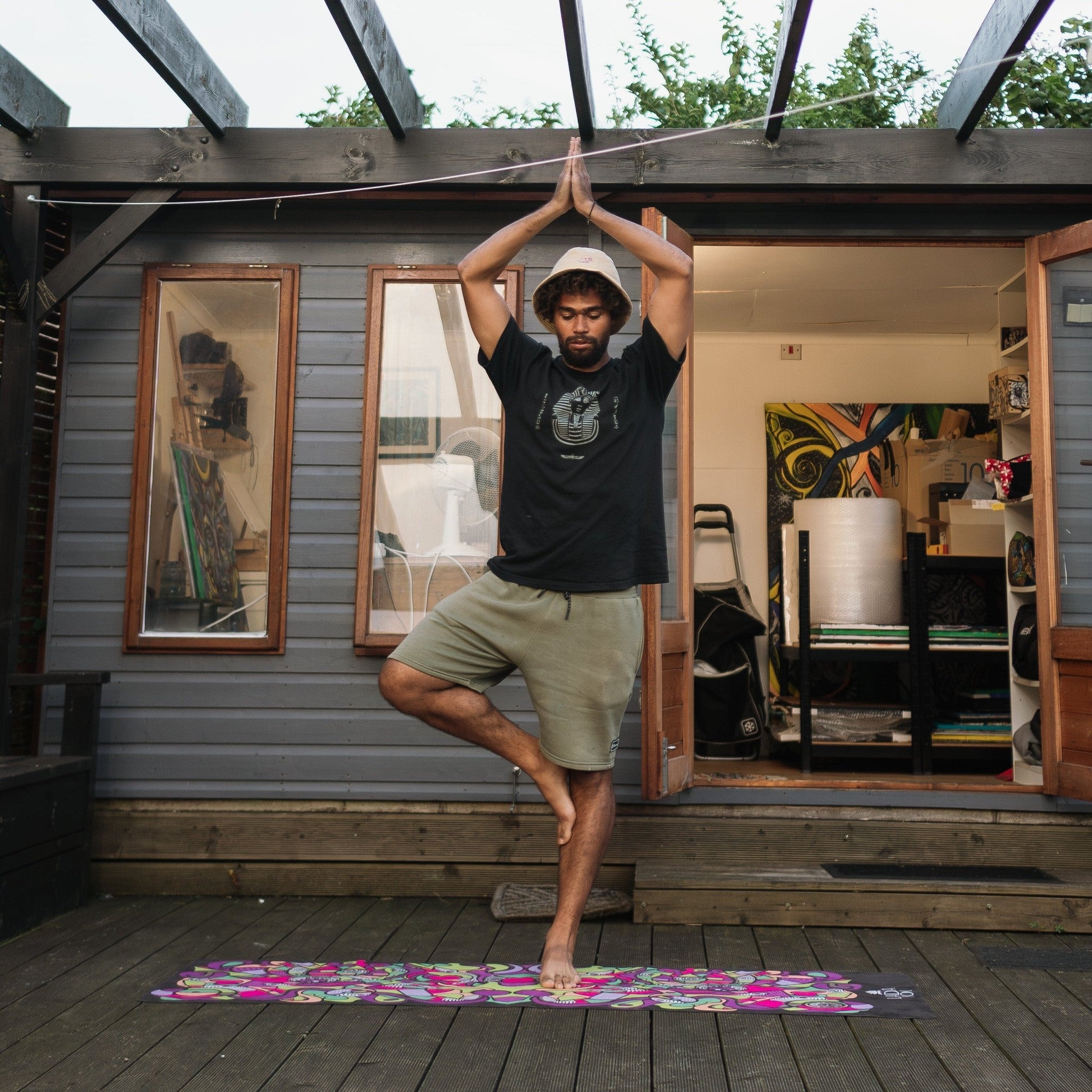 Person practicing yoga on a colorful mat in a studio setting with wooden walls and art.