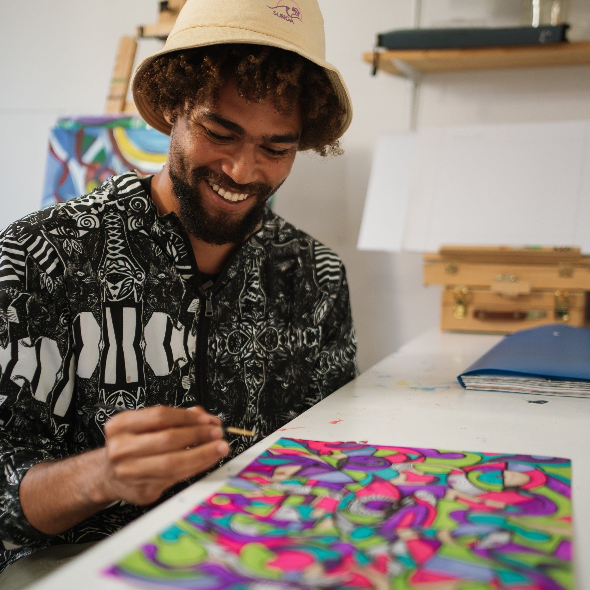 Man smiling while working on a colorful art project at a table.