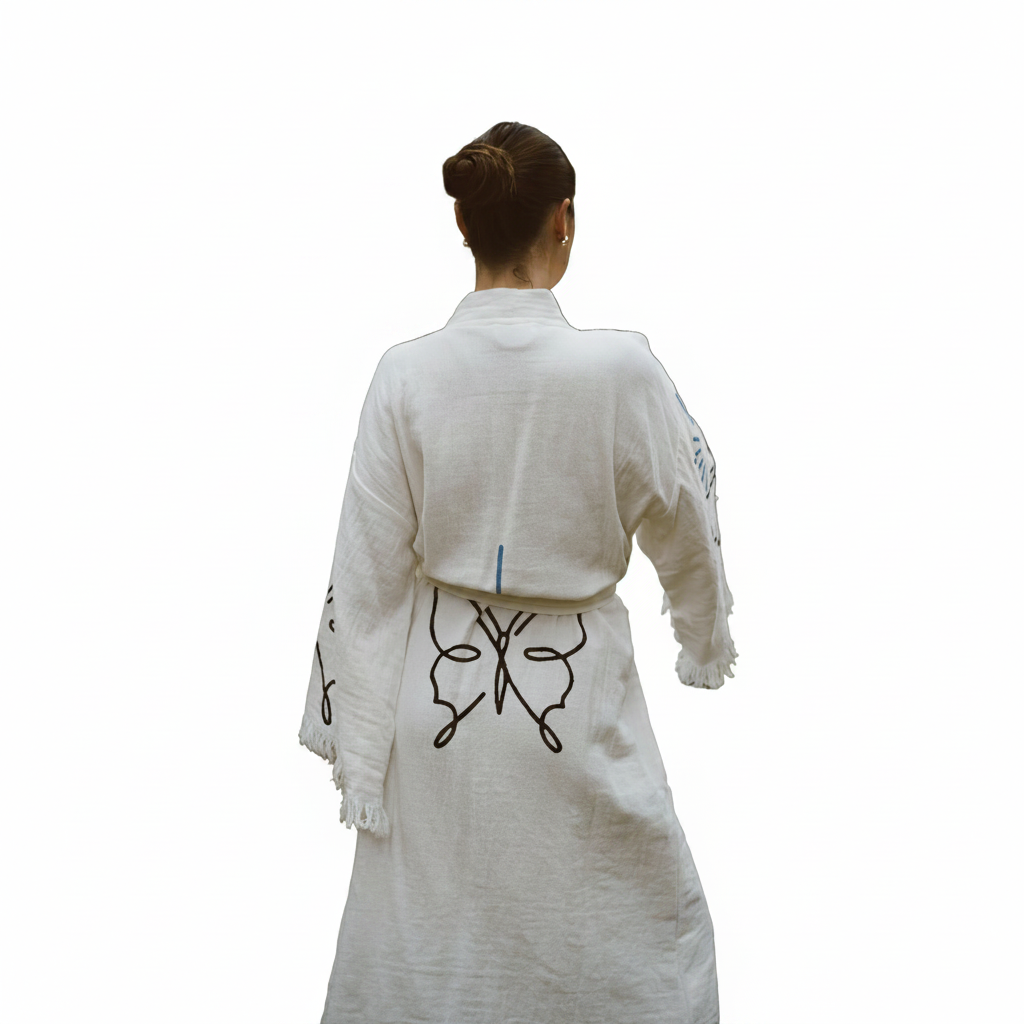 A woman viewed from behind wearing a white kimono robe with black line-art butterfly embroidery on the back and sleeves, set against a plain white background.