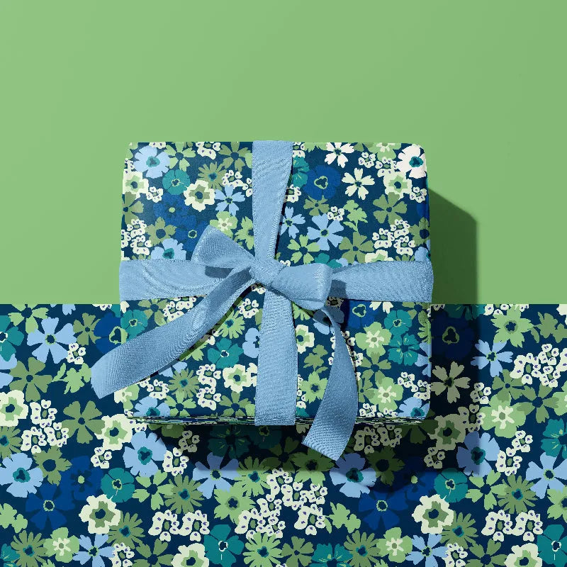 Floral-patterned gift wrap with a blue ribbon on a green background