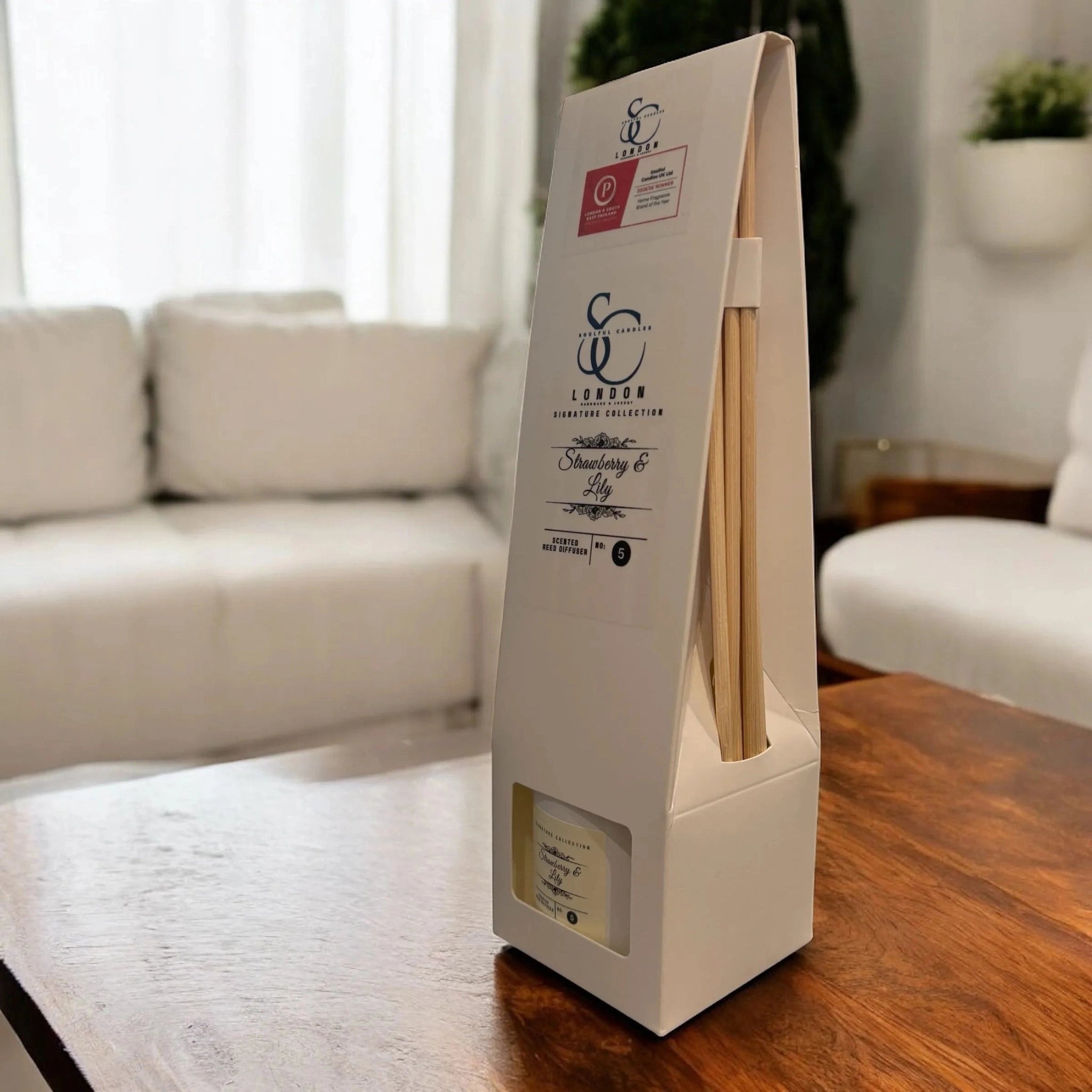Reed diffuser product packaging on a wooden table with a blurred living room background