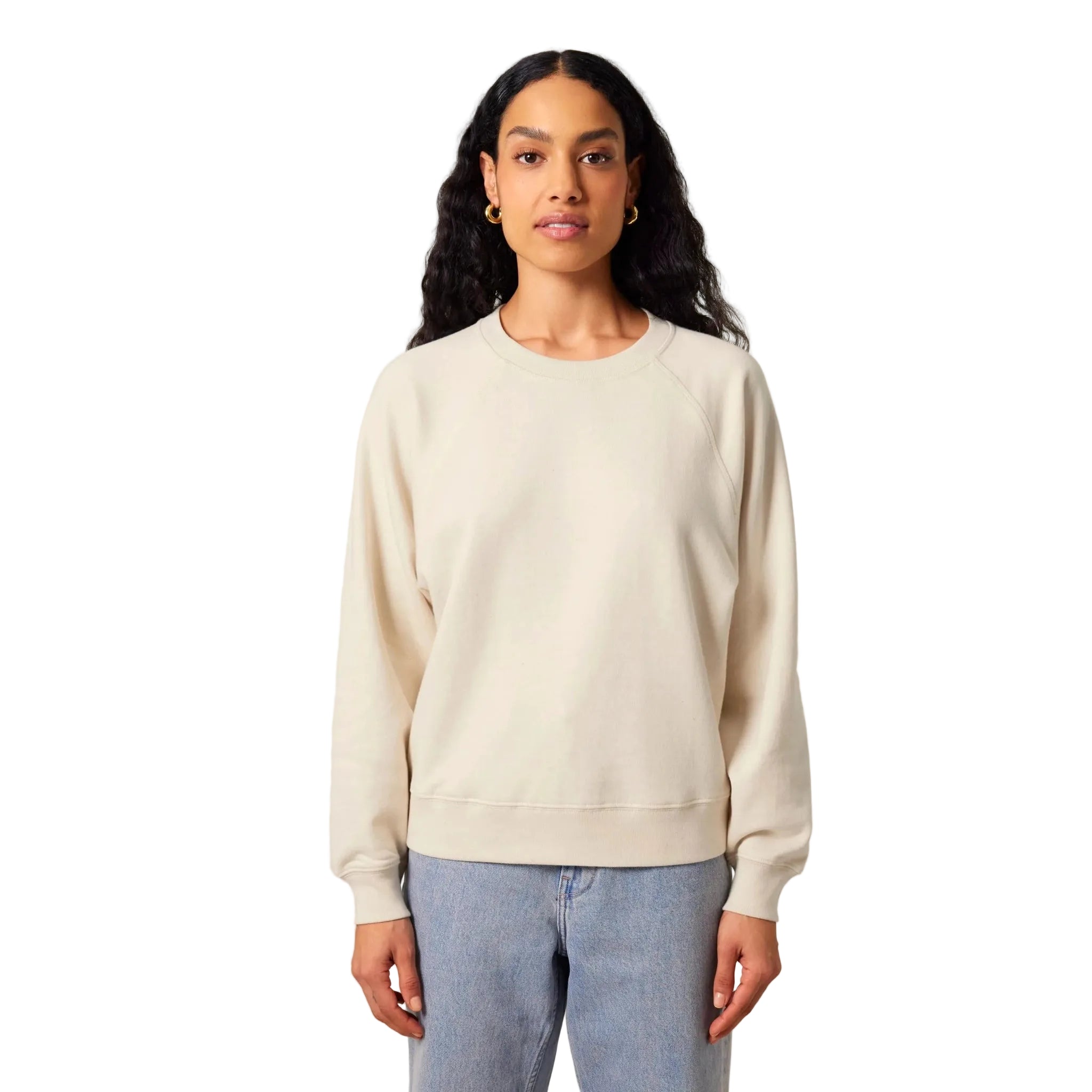 Woman wearing a cream sweatshirt and light blue jeans on a white background