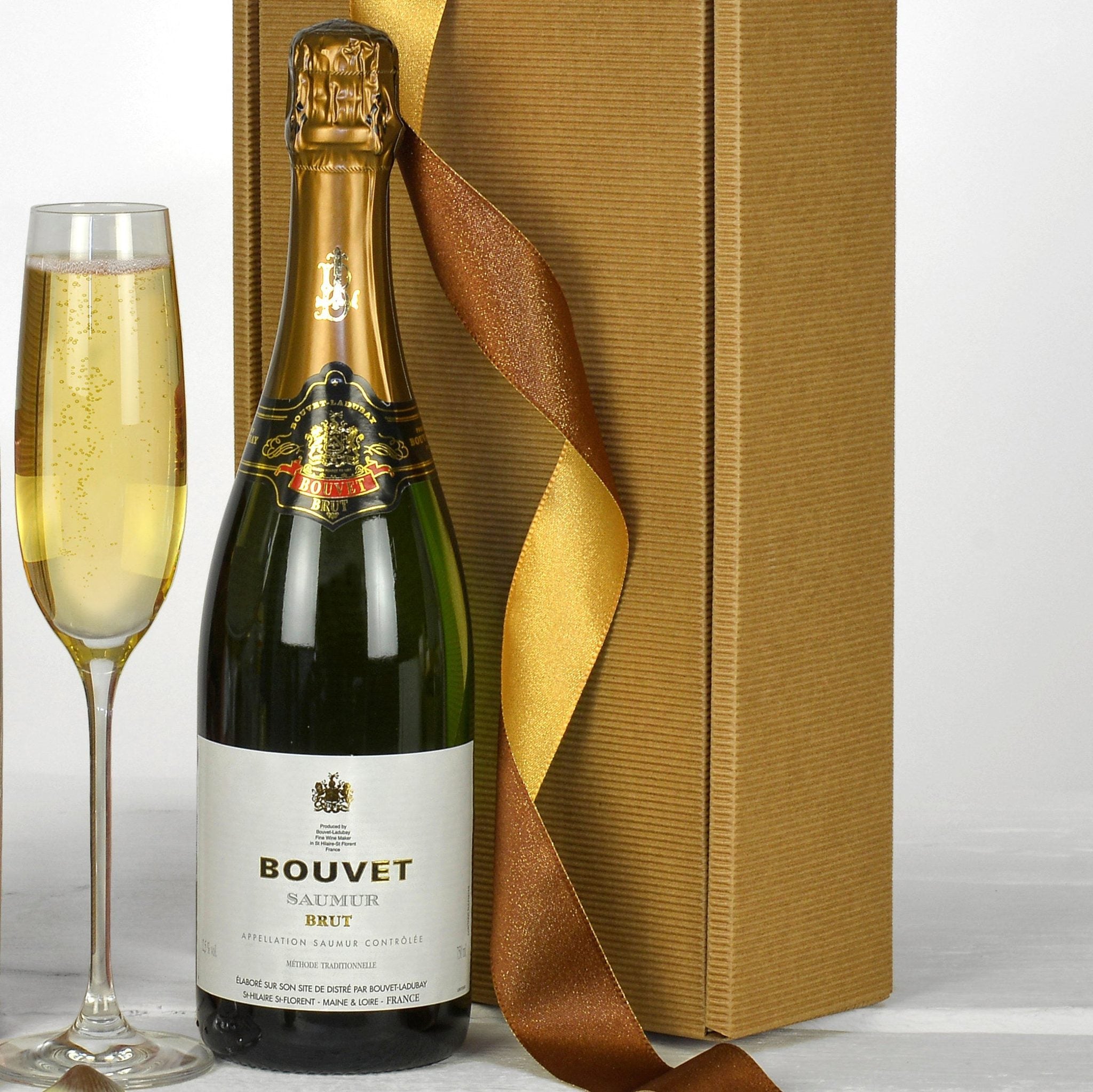 Bottle of Bouvet sparkling wine with a glass and gold box on a white background