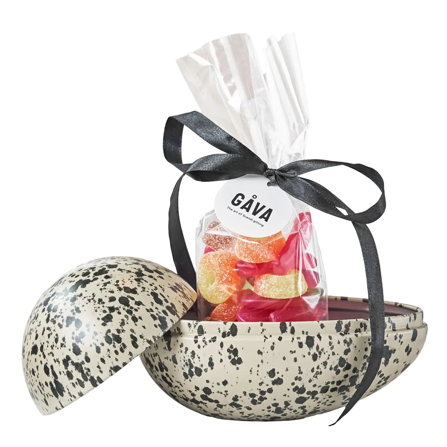 Speckled Easter egg with a clear bag of sweets tied with a black ribbon on a white background
