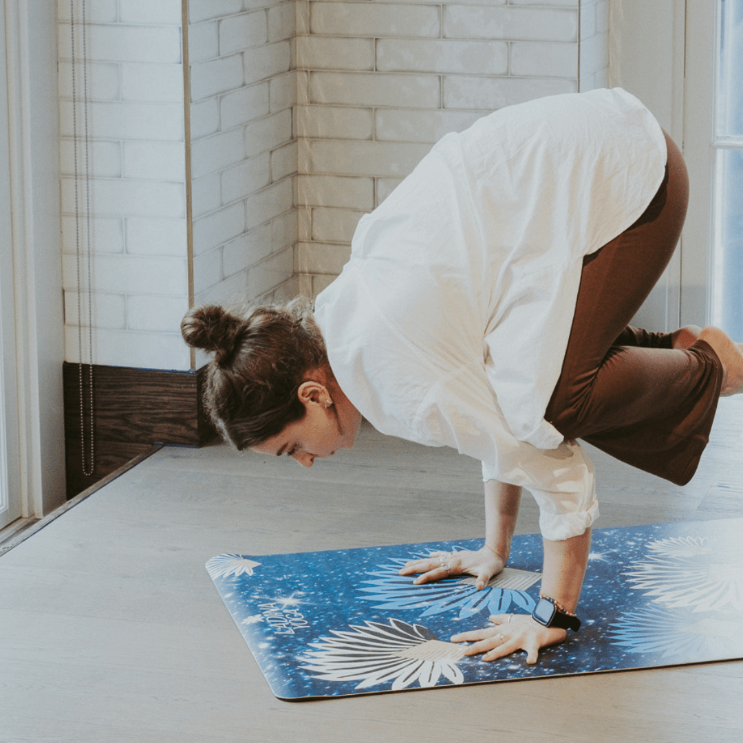 Person practicing yoga on a blue mat with a white brick wall background