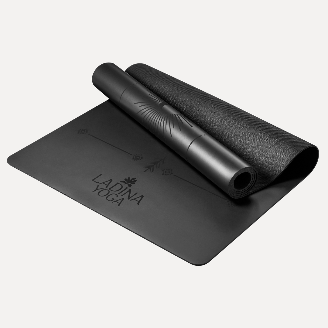 Black yoga mat with rolled-up mat on a light gray background