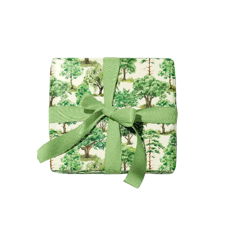 A gift-wrapped present, featuring a green forest tree pattern on a cream background, tied with a matching green ribbon and bow, isolated on a white background.