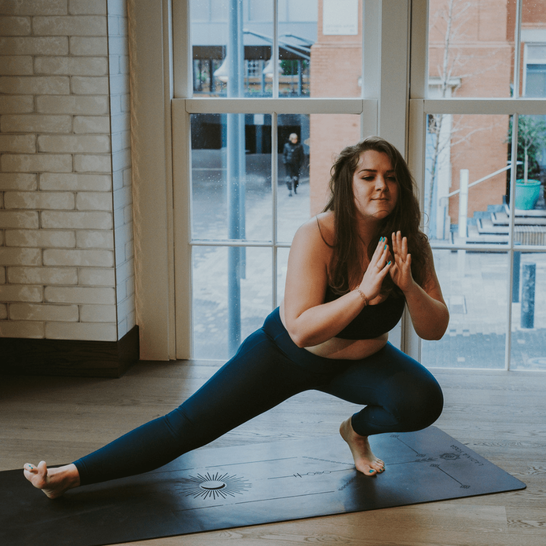 Woman practicing yoga in a studio with large windows