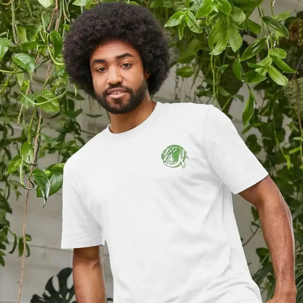 A man wearing an organic white t-shirt with a green logo in front of green plants