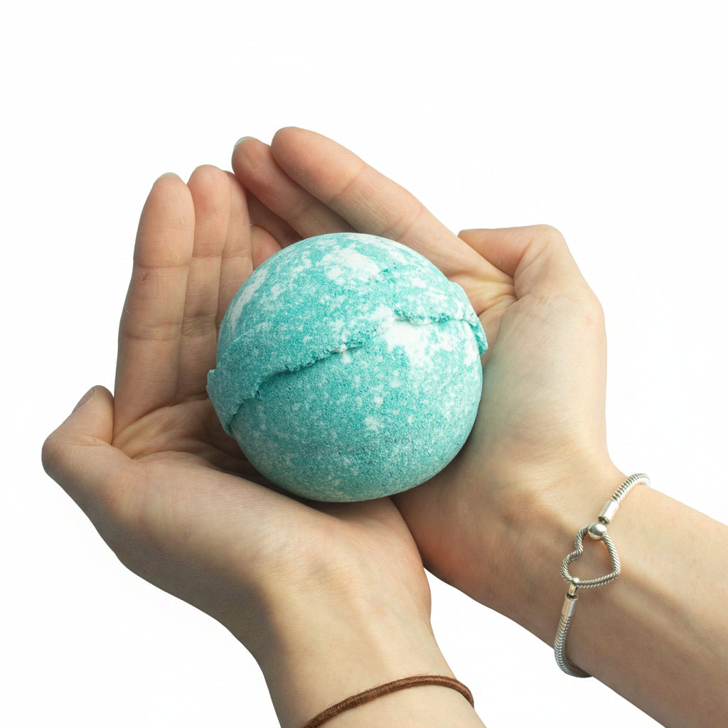 Turquoise bath bomb held between two hands against a white background