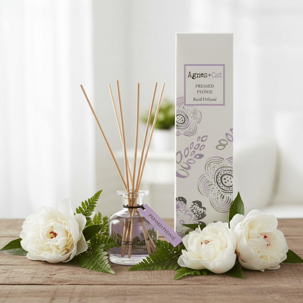 Aromatherapy diffuser with reeds and packaging on a wooden surface with flowers.