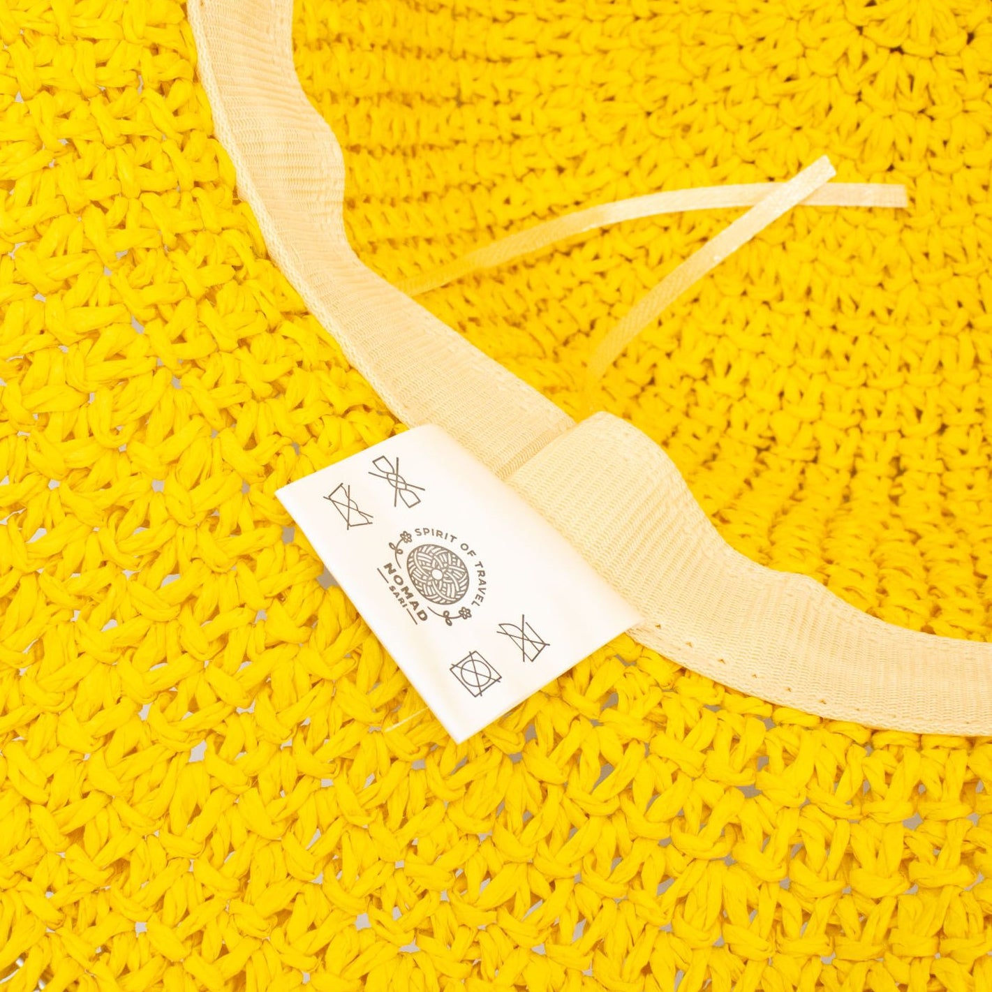 Yellow woven floppy straw hat with a visible brand tag on a white background