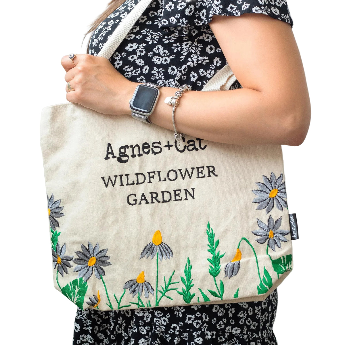 Person carrying the natural-coloured Agnes + Cat Wildflower Garden tote with purple floral embroidery over their shoulder