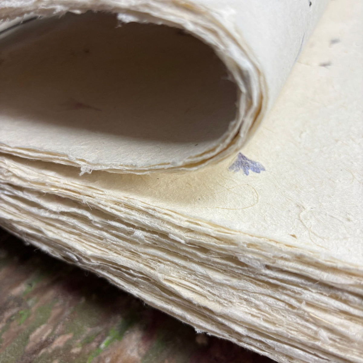 Close-up of a stack of handmade Lokta paper with real pressed cornflower petals