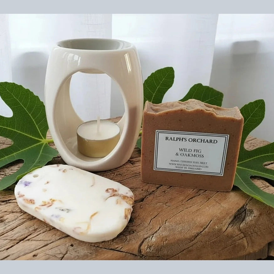 Wax melt, candle, and wax melt burner on a wooden surface with green leaves
