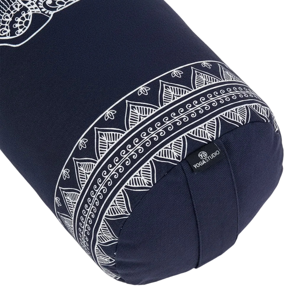 A navy blue cylindrical yoga bolster pillow with white geometric and mandala patterns, featuring a small black brand tag that reads 'YOGA STUDIO'.