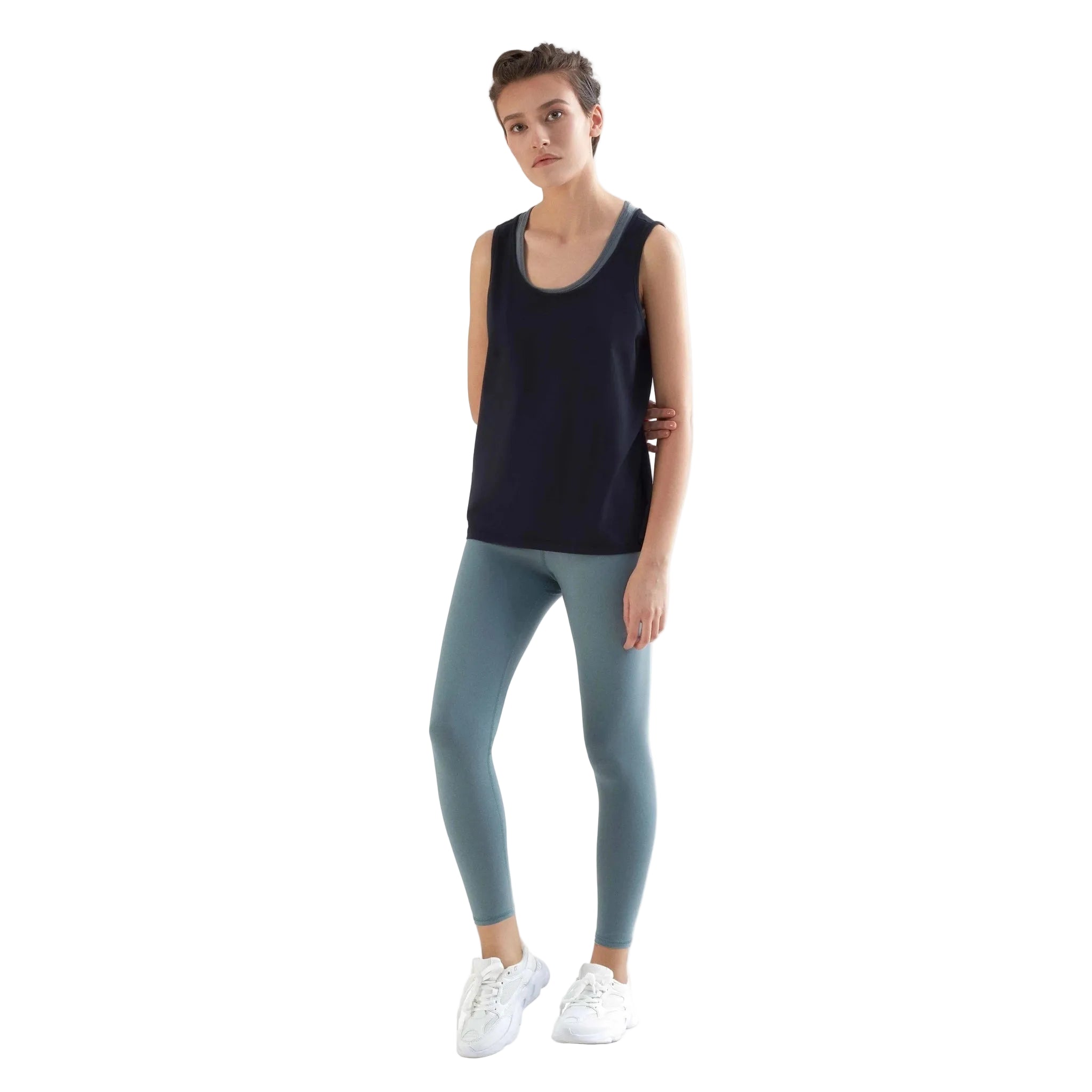 Woman wearing a black tank top and light blue leggings on a white background