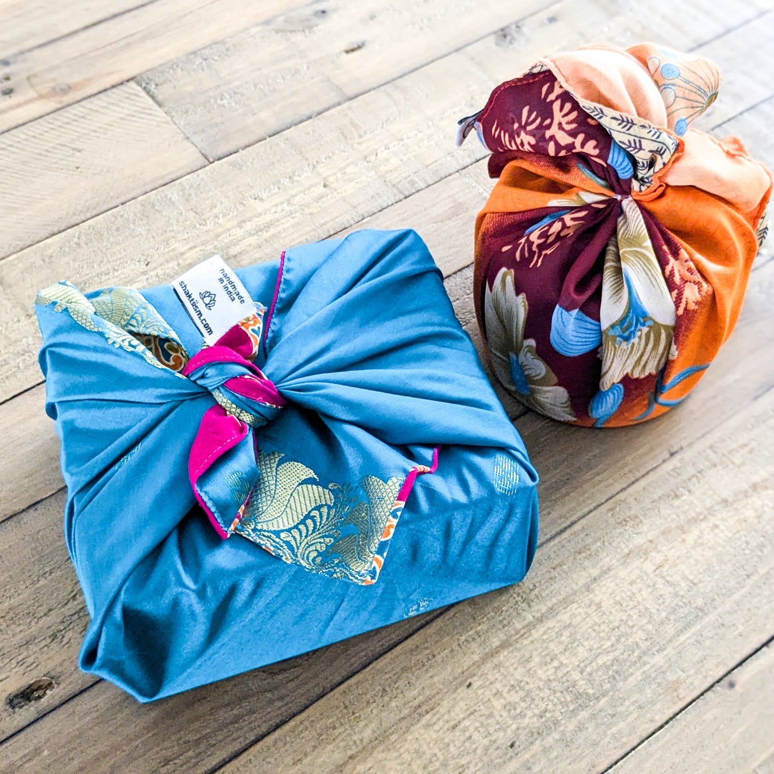 Two colourful fabric-wrapped gifts on a wooden surface