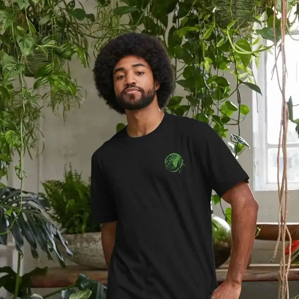 Man wearing a black t-shirt with a green logo in a room with plants