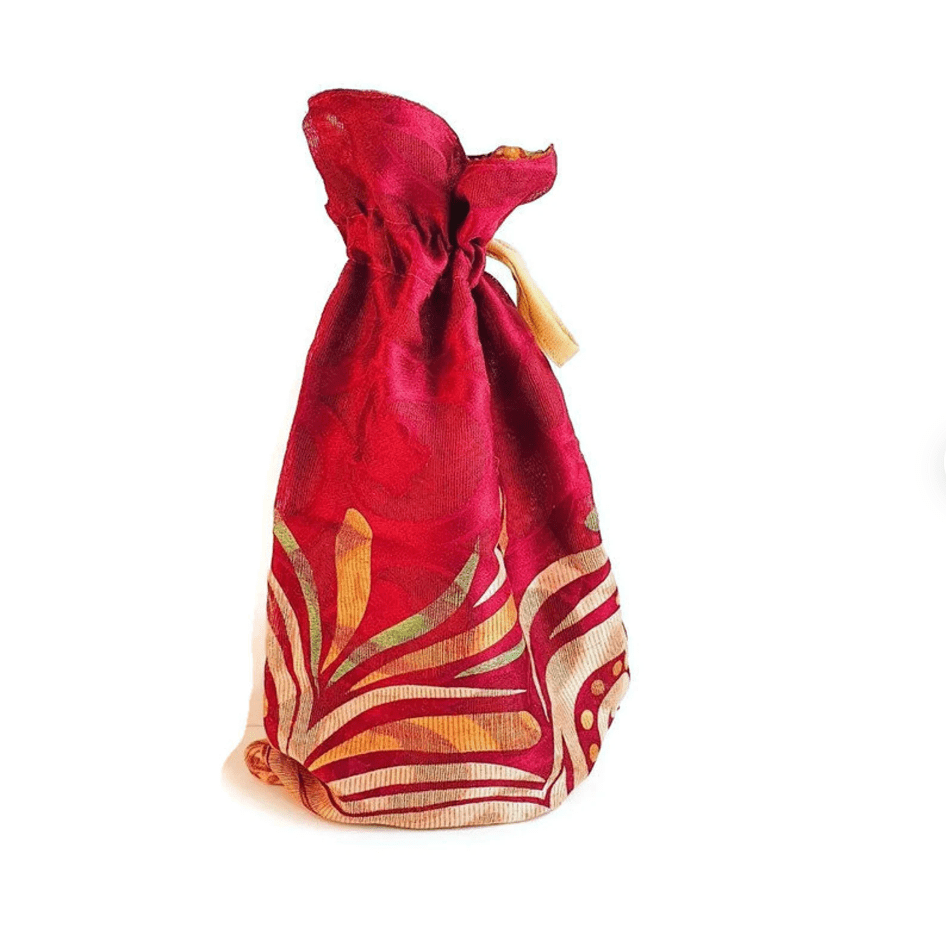 Red fabric drawstring gift bag with gold patterns on a white background