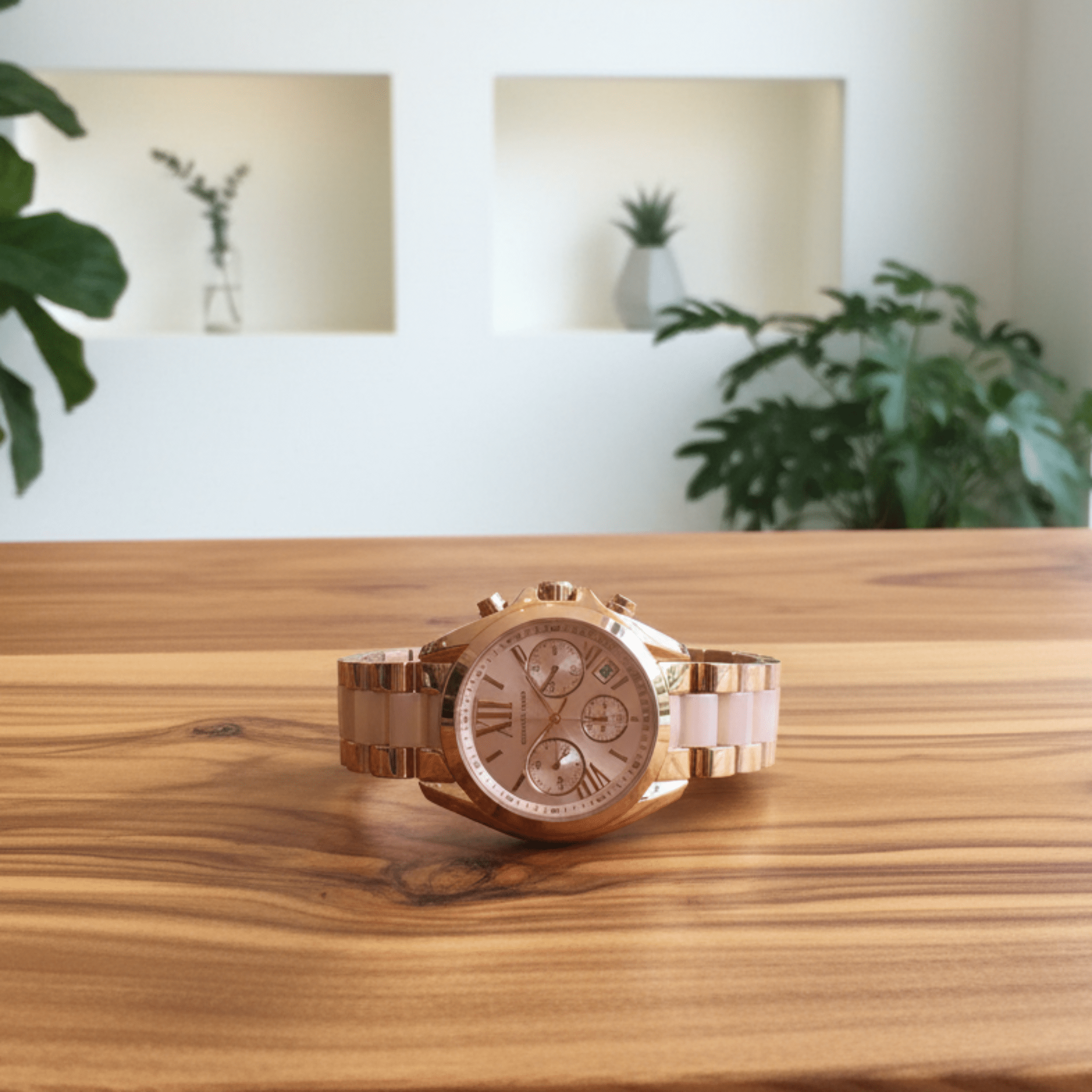 Rose gold watch on a wooden surface with a blurred indoor background
