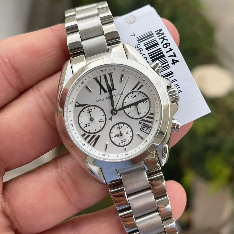 Silver watch held in a hand with a blurred background