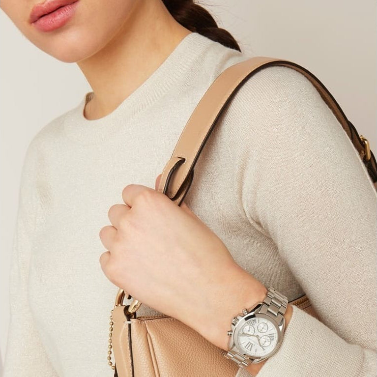 Person wearing a silver watch on a beige background