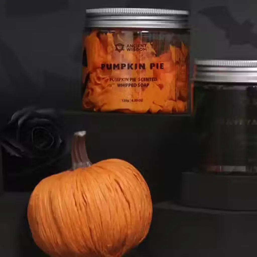 Jar of pumpkin pie-scented whipped soap with a small pumpkin on a dark background