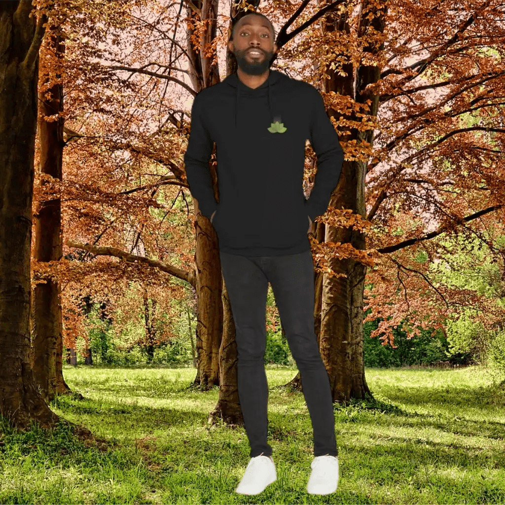 Man wearing a black hoodie with a green logo in an autumn forest