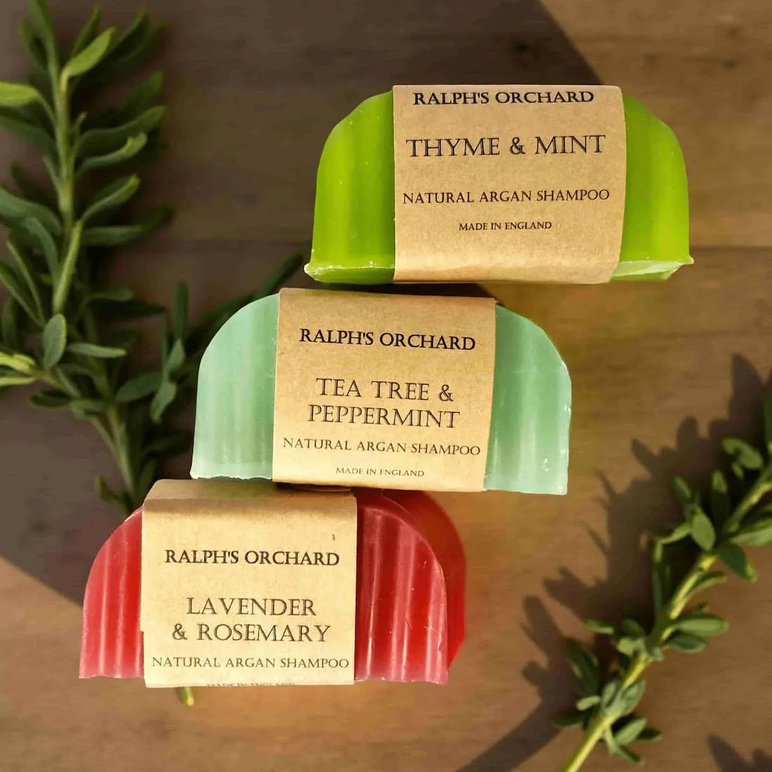 Three bars of Ralph's Orchard natural argan shampoo with labels on a wooden surface.
