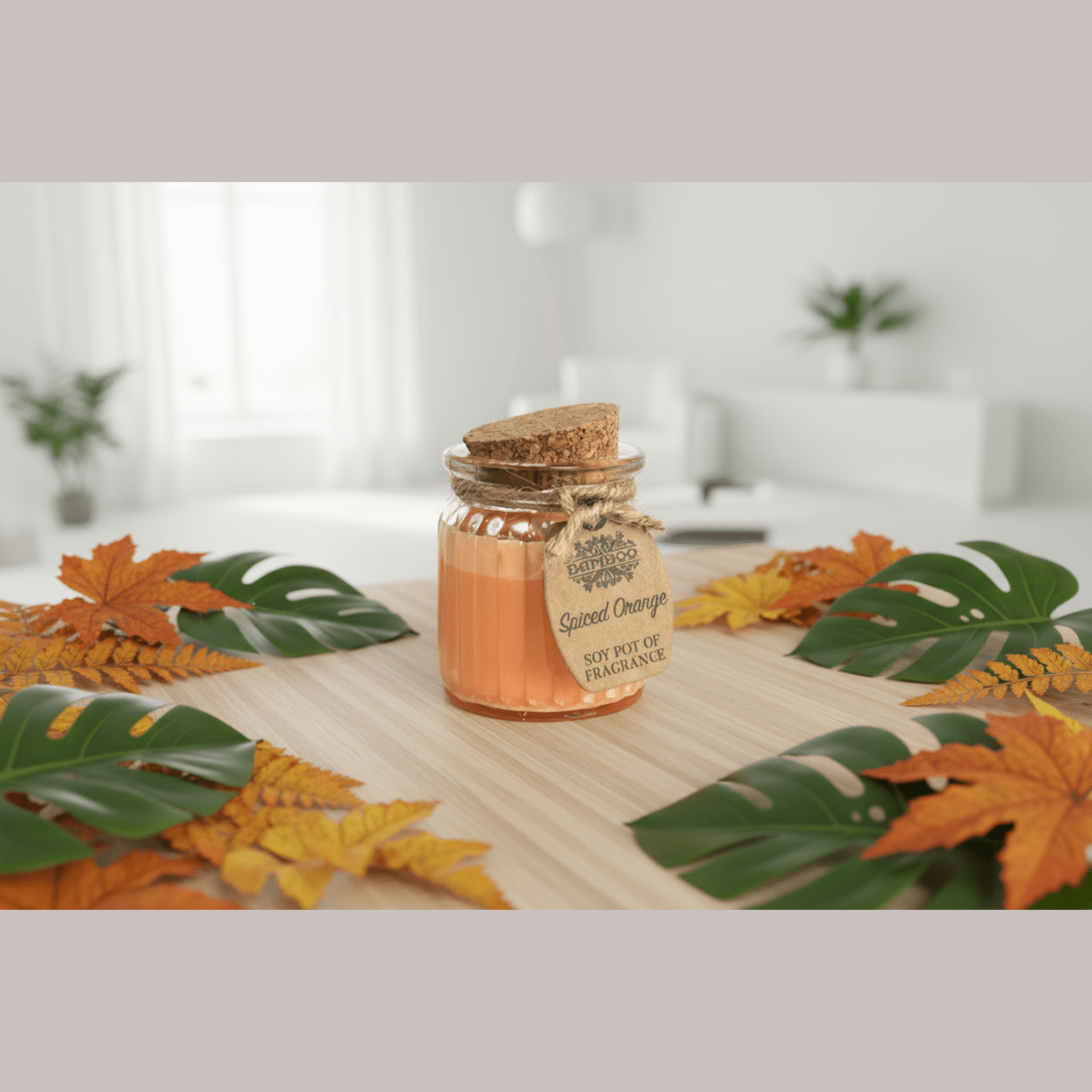 Scented candle in a decorative jar with autumn leaves on a wooden surface