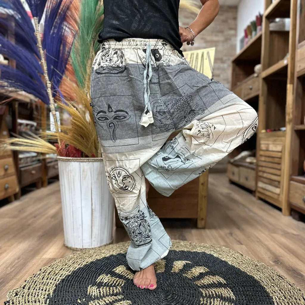 Person wearing patterned festival pants in a room with wooden shelves and decor.