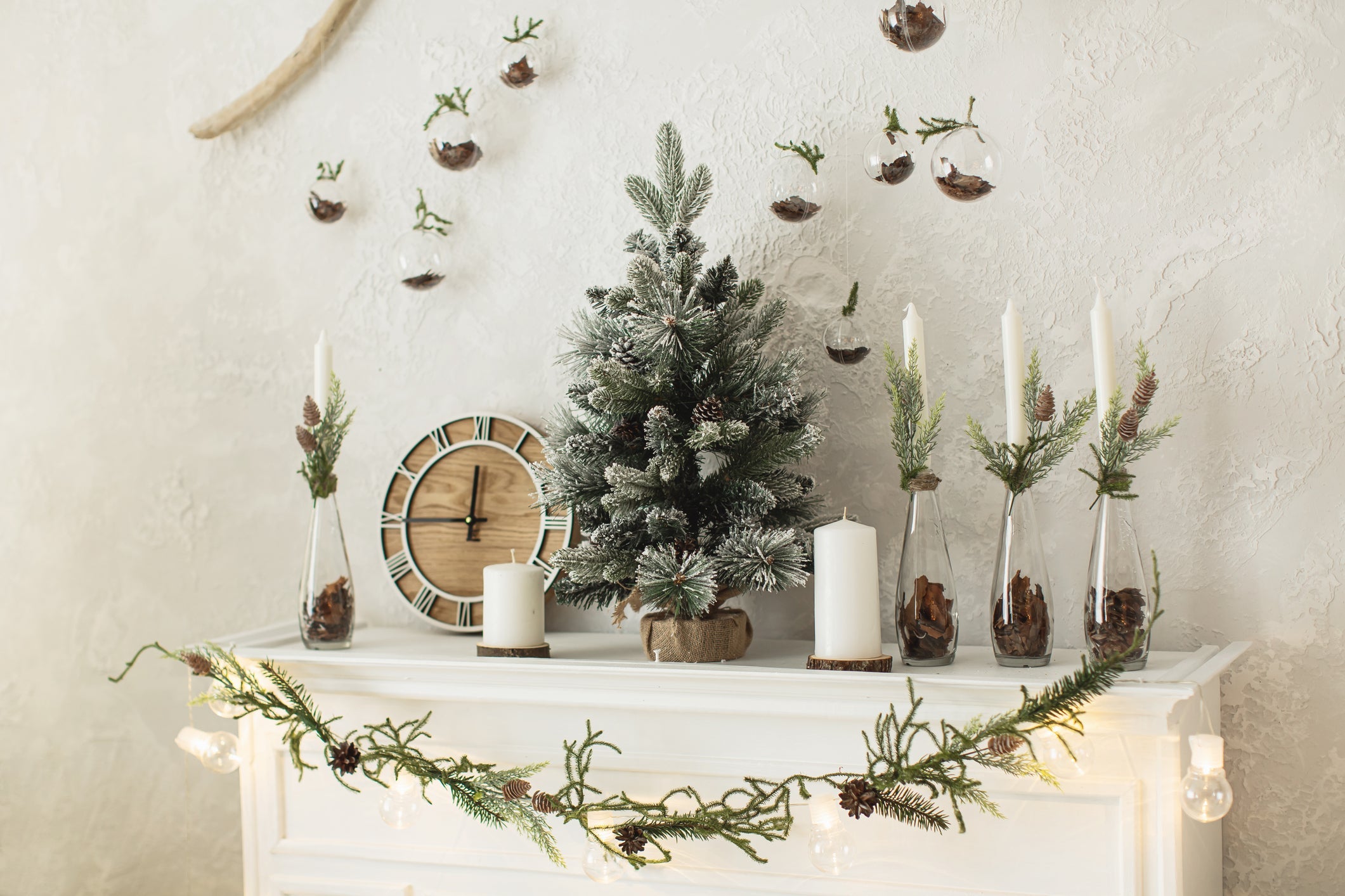 Christmas table decoration with green branches baubles. candles and silver leaves on a wooden table.