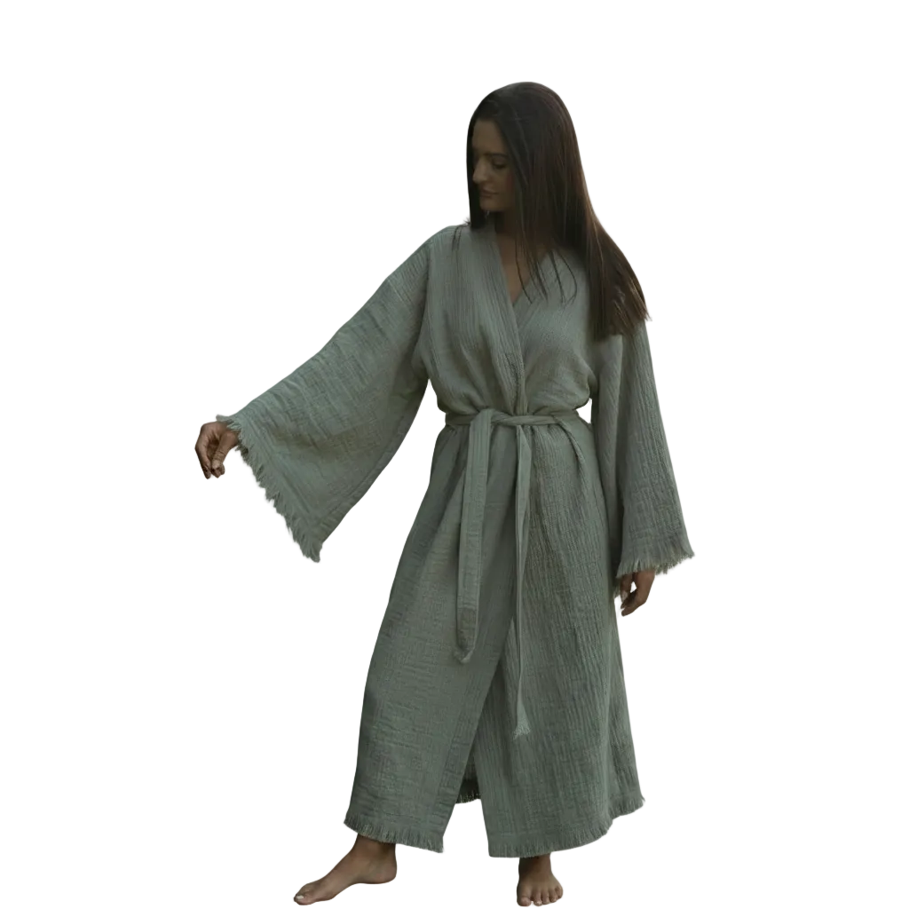 A woman modelling a long, loose sage green cotton robe with wide bell sleeves and a matching waist tie, shown against a plain white background.