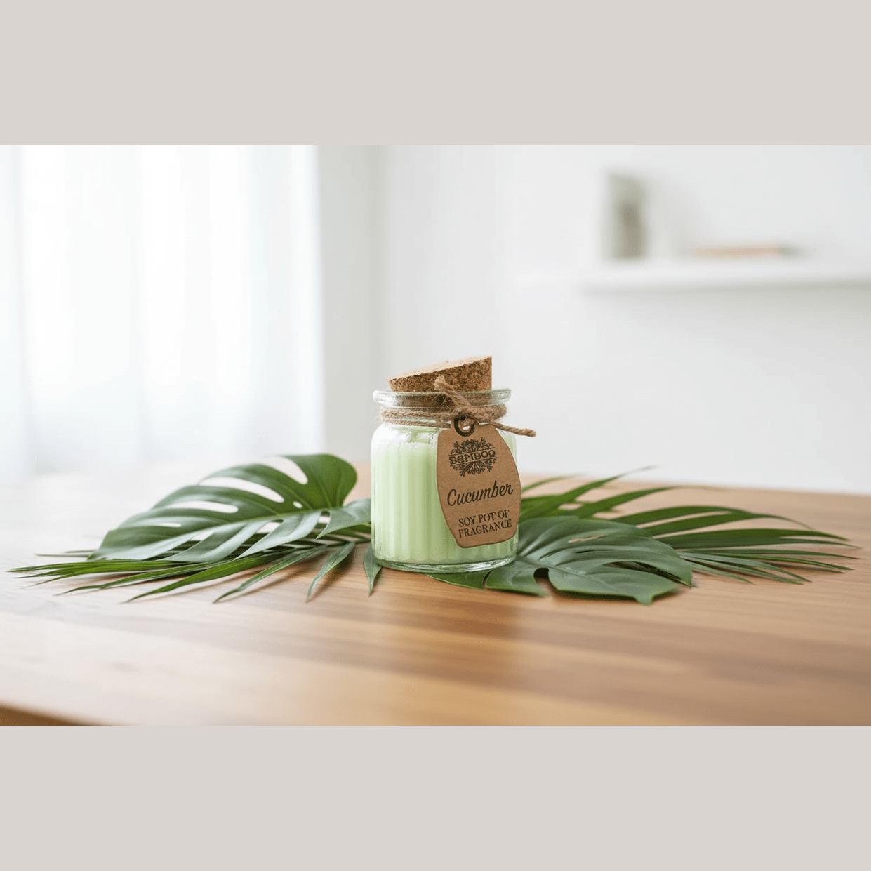 Cucumber-scented candle in a glass jar with a wooden lid on a wooden surface with palm leaves.